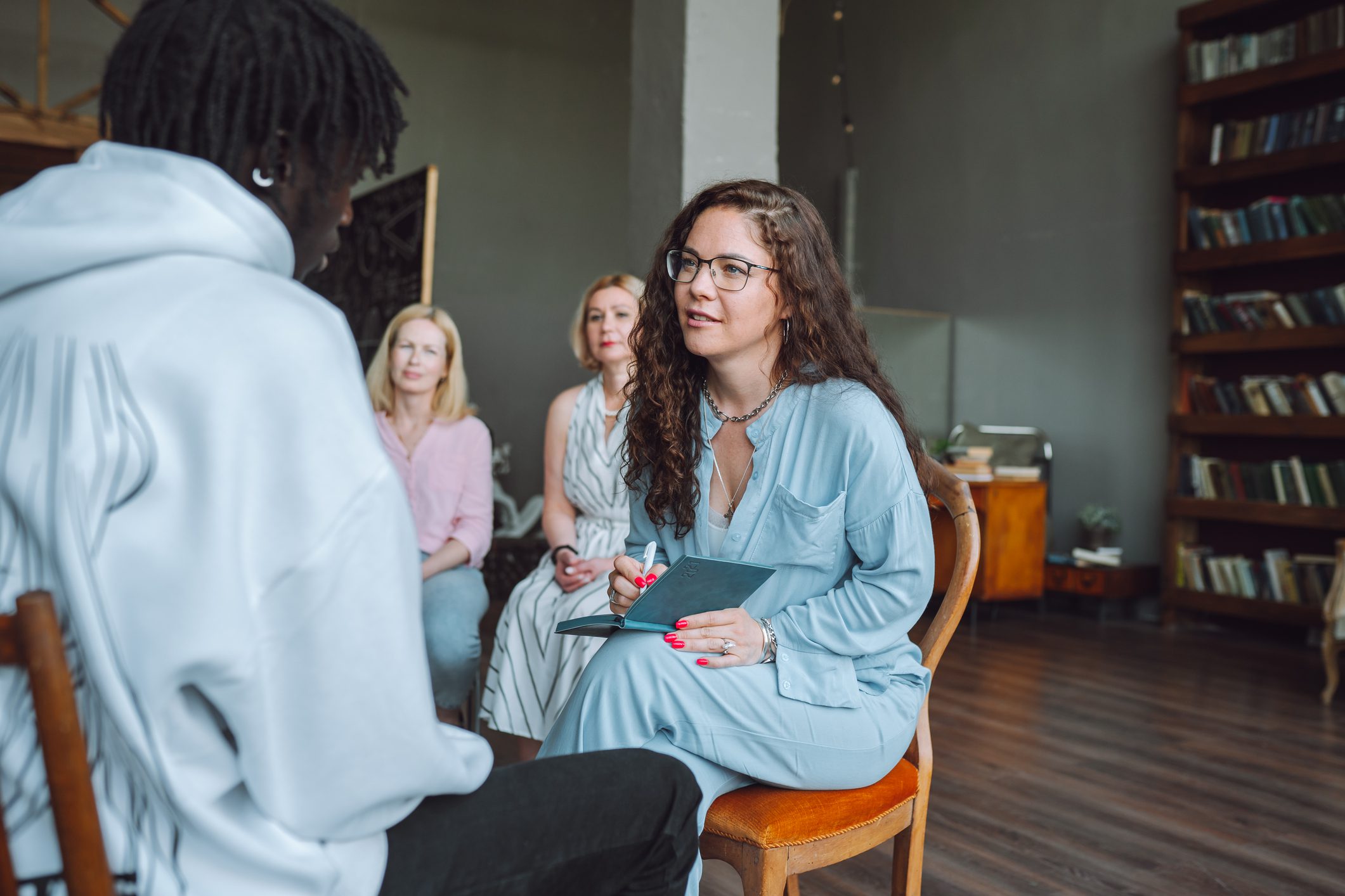 Psychiatrist takes notes on patient struggling with addiction during group therapy